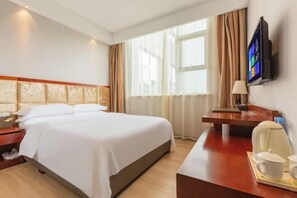 A hotel room with a bed, a desk with a chair, a TV, and a window with curtains. - Joy Opulence Hotel (Guiyang)