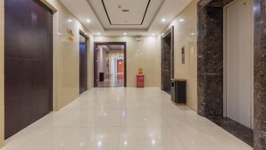 A clean, modern hallway with a shiny tiled floor, a marble wall, and a door on the right.