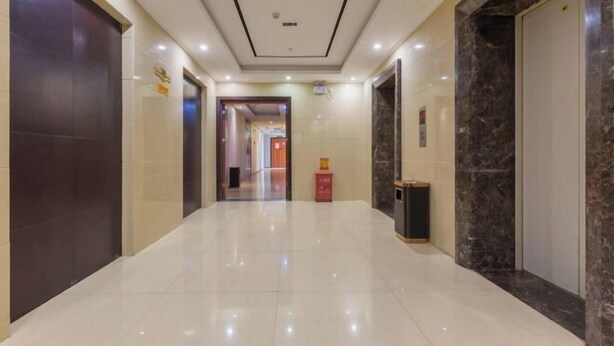 A clean, modern hallway with a shiny tiled floor, a marble wall, and a door on the right. - Joy Opulence Hotel (Guiyang)