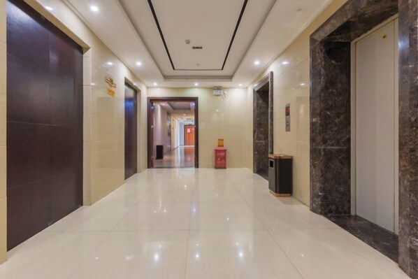 A clean, modern hallway with a shiny tiled floor, a marble wall, and a door on the right. - Joy Opulence Hotel (Guiyang)