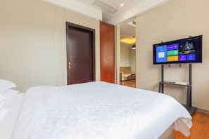 Una habitación de hotel con una cama grande, un televisor montado en la pared y un armario.