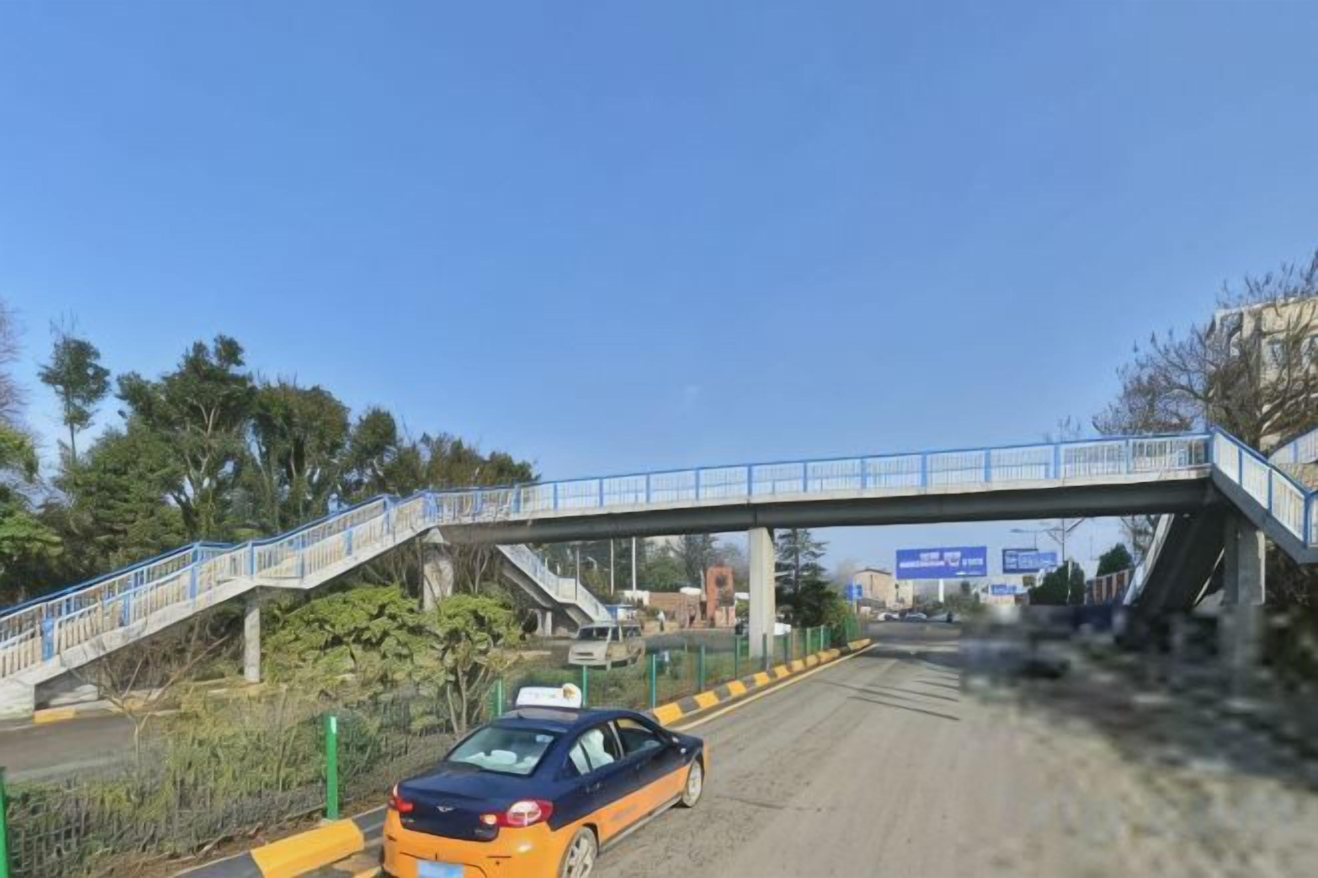 Ein Auto auf einer Straße mit einer Fußgängerbrücke darüber.