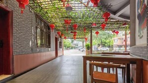 A corridor with a brick wall, a wooden bench, and a table with chairs.