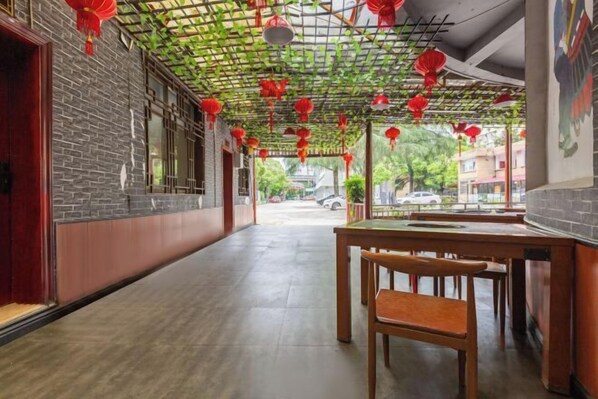 A corridor with a brick wall, a wooden bench, and a table with chairs. - Joy Opulence Hotel (Guiyang)