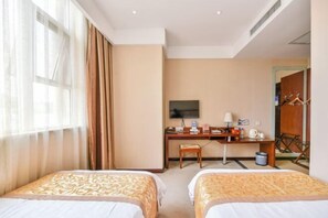 Two single beds with matching headboards, a desk, and a television are featured in this well-maintained room.