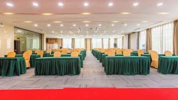 A conference room with rows of tables and chairs, carpeted flooring, and a red carpet leading to the entrance.