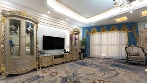 Ein luxuriöses Wohnzimmer mit kunstvollen Möbeln, einem großen Flachbildfernseher und einem gemusterten Teppich.