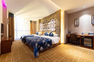 Una habitación de hotel con una cama grande, un escritorio, una silla y un minibar.