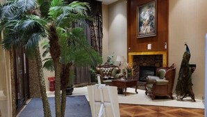 Eine Lobby mit Kamin, einer Pfauenstatue und einem Gemälde an der Wand.