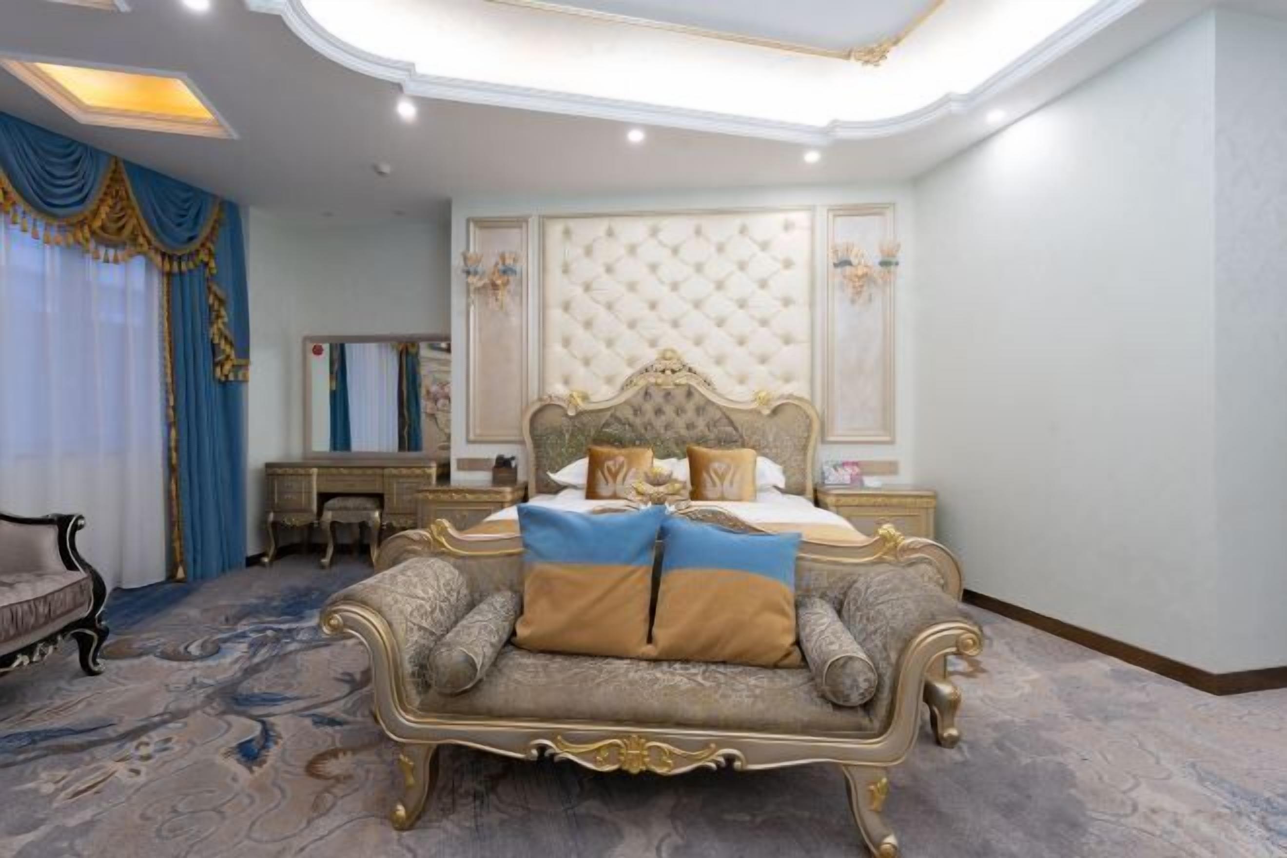 A luxurious bedroom with a large bed, ornate headboard, and a classic armchair.