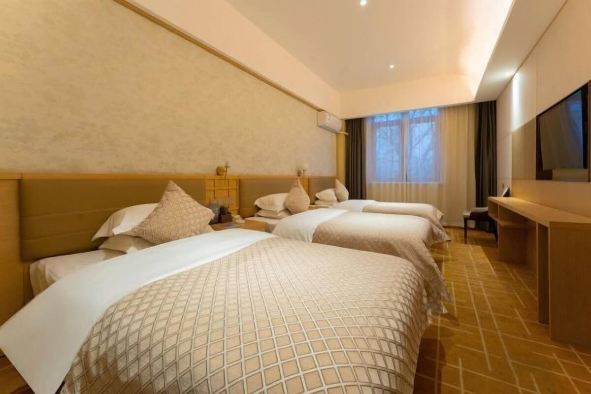A hotel room with two beds, a desk, and a TV.