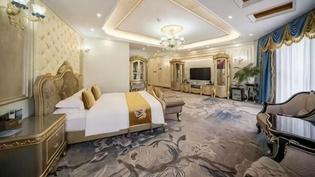 Ein luxuriöses Hotelzimmer mit einem großen Bett, einem Fernseher, einer Sitzecke und einer dekorativen Decke.