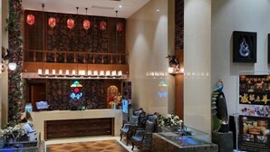 Eine Hotellobby mit Rezeption, Sitzgelegenheiten und Dekorationselementen wie Laternen und Wandbildern.