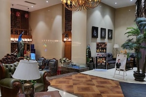 A lobby with a reception desk, seating area, and decorative elements like a peacock sculpture and wall art.