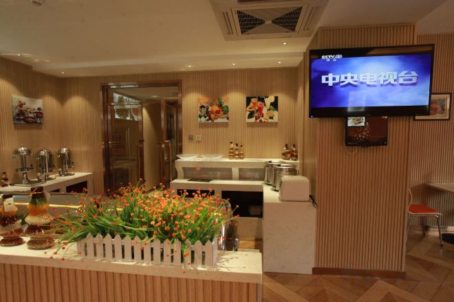 Eine Hotelhalle mit einer Rezeption, einem Fernseher und einer Zimmerpflanze.