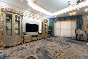 Una sala de estar lujosa con muebles ornamentados, un televisor de pantalla plana grande y una alfombra estampada.