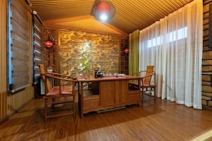Comedor de madera con pared de piedra, dos sillas, una mesa y una lámpara colgante.