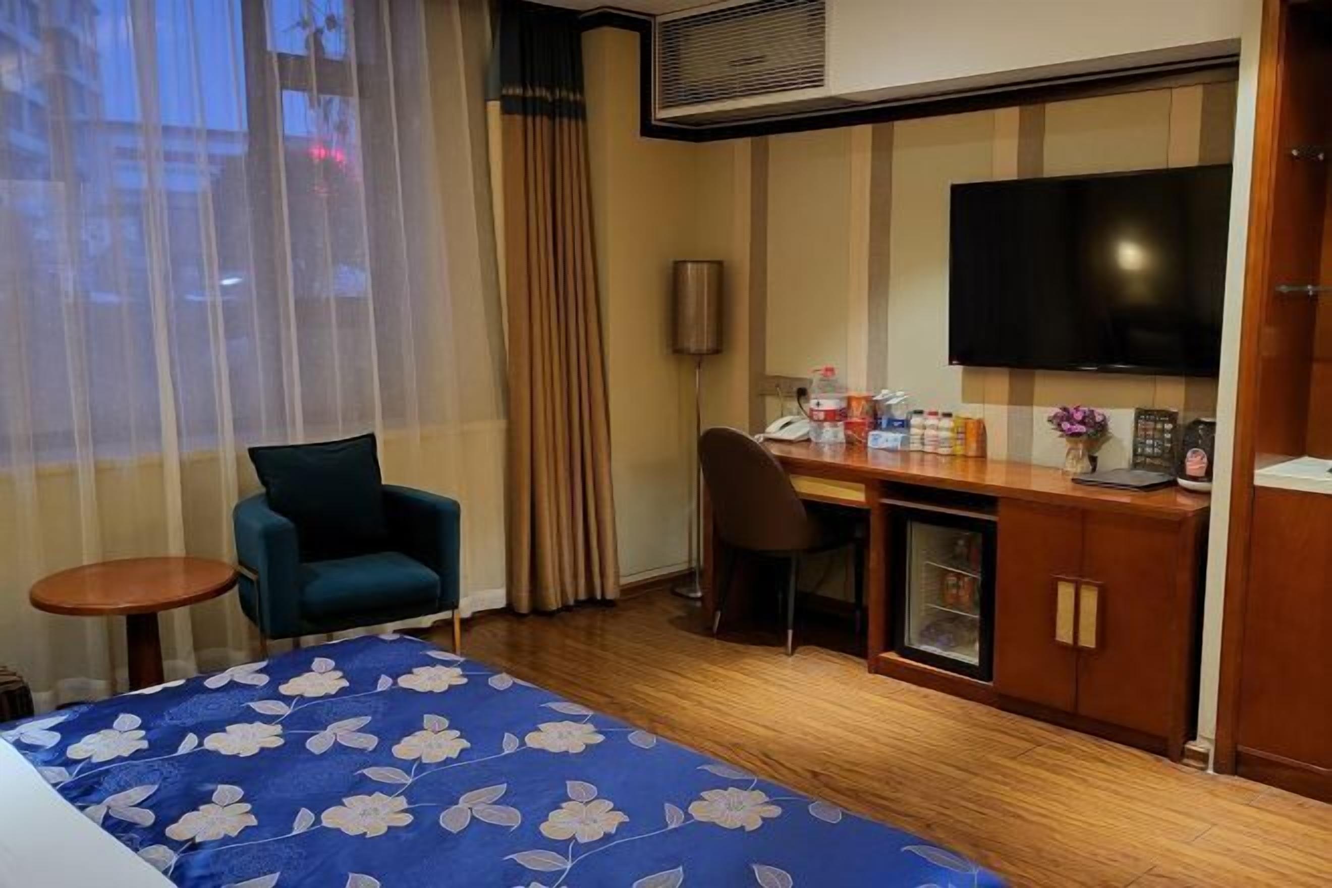 Une chambre d’hôtel équipée d’un lit, d’un bureau, d’une chaise, d’une télévision et d’un mini-bar.