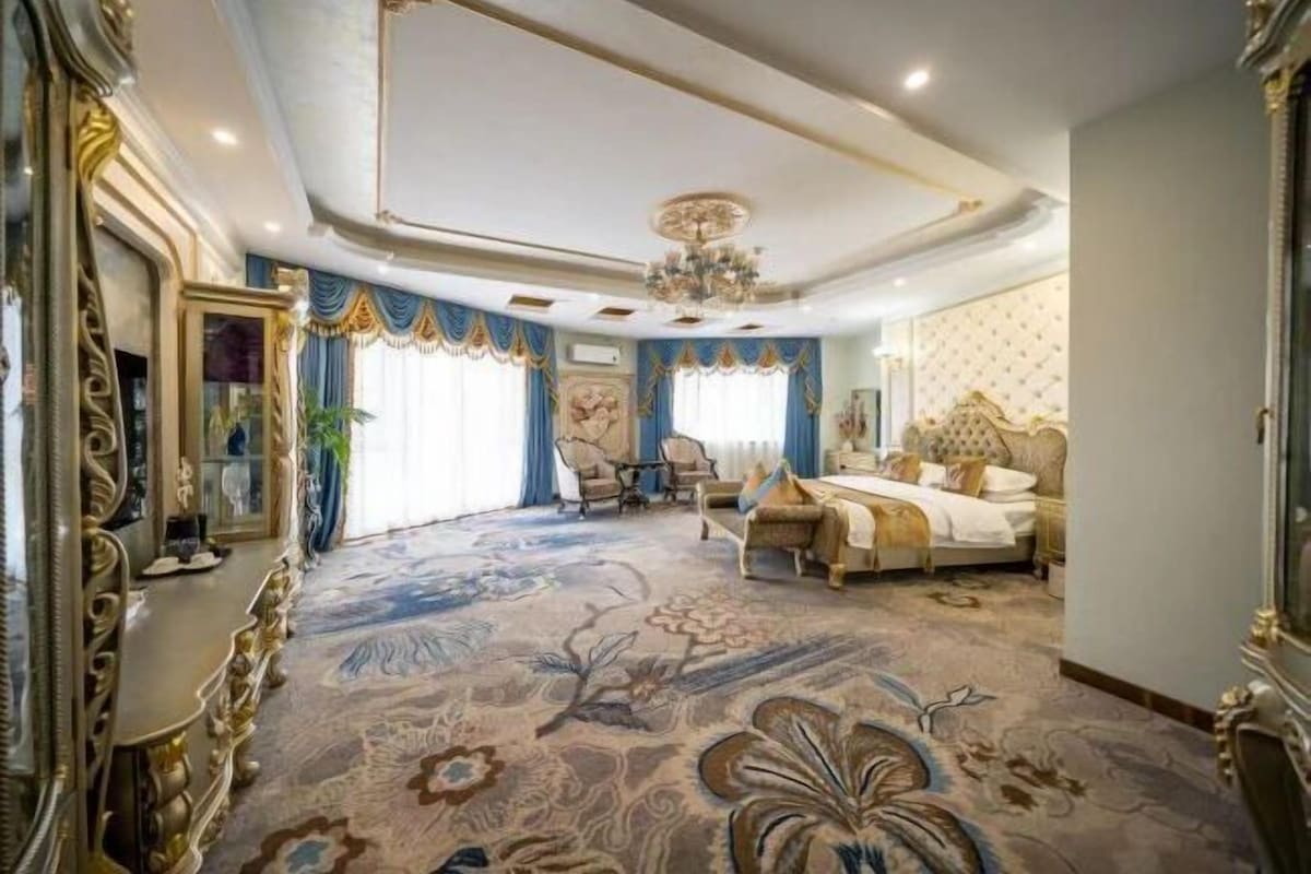 A luxurious bedroom with a large bed, ornate furniture, and a patterned carpet.