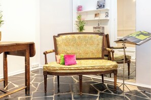 A chair with floral upholstery and a wooden frame, positioned on a stone floor. - Fabulous 4BD Apartment 5 mins to the Eiffel Tower (Paris)