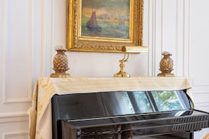 Un piano doté d’un cadre doré et recouvert d’une nappe de couleur or, flanqué de deux vases dorés richement décorés.