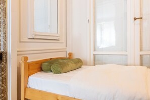 A single bed with a wooden headboard, white bedding, and a green pillow. - Fabulous 4BD Apartment 5 mins to the Eiffel Tower (Paris)