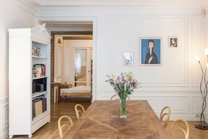 A dining room with a wooden table, chairs, a white cabinet, and artwork on the wall. - Fabulous 4BD Apartment 5 mins to the Eiffel Tower (Paris)