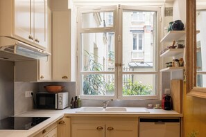 A kitchen with a large window, a microwave, a sink, and a dishwasher.