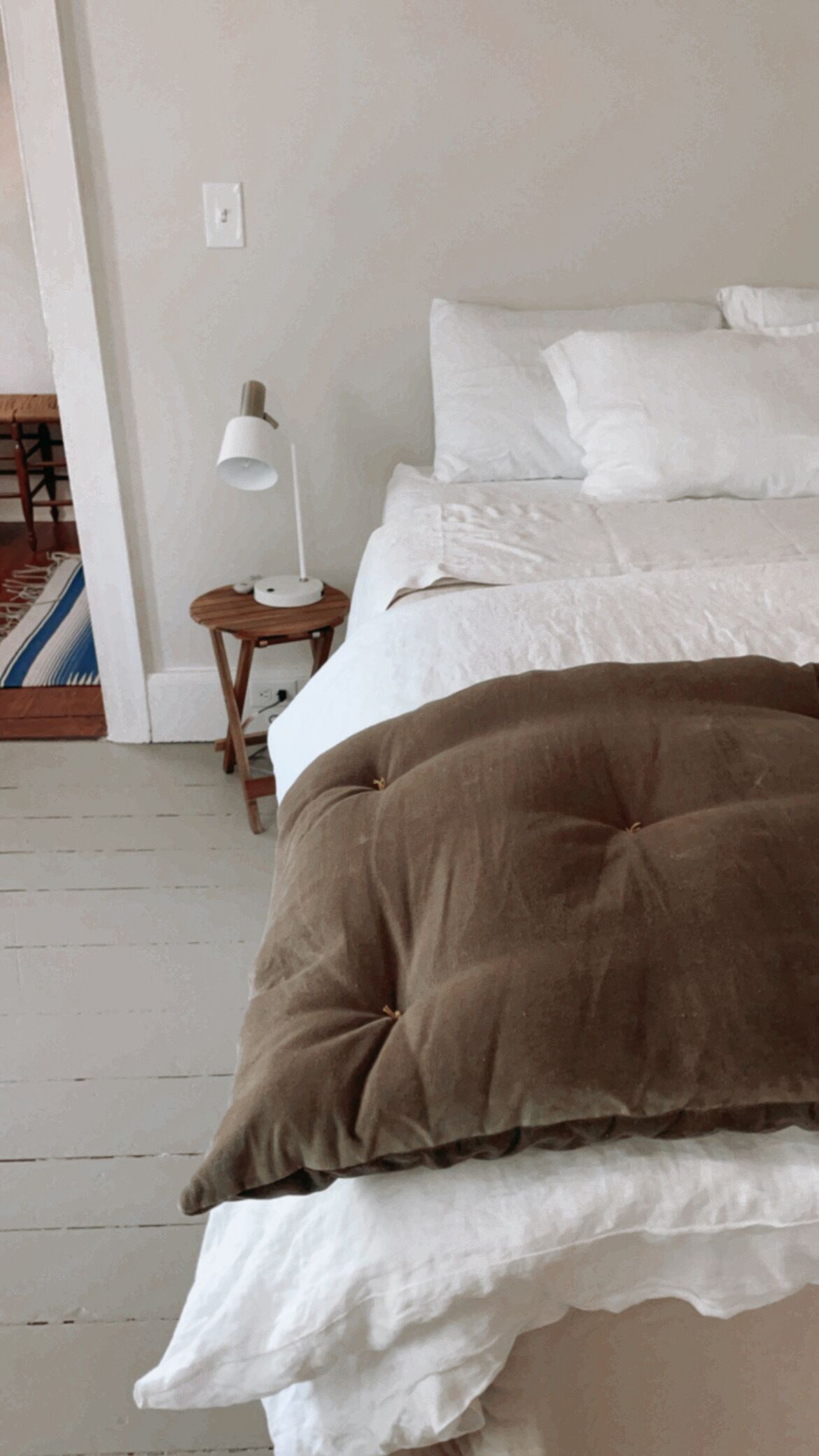 Une chambre à coucher avec un lit, des oreillers, une table de chevet avec une lampe et un tapis.