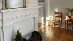 Ein Zimmer mit Kamin, großem Spiegel und Holzboden.