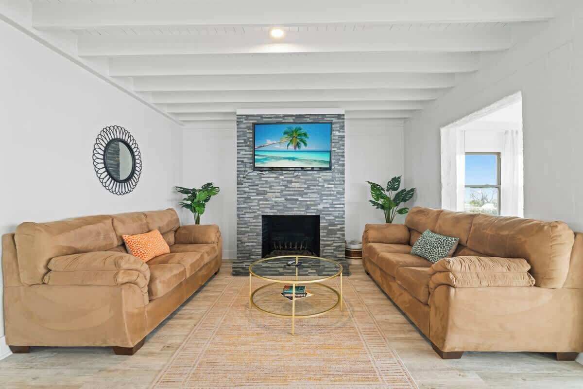 A living room with two sofas, a fireplace, a TV, and a large window.