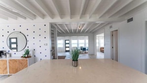 Una cocina amplia con una isla central, un espejo redondo y plantas en macetas.