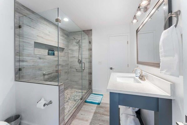 Une salle de bain moderne avec une douche à parois de verre, un lavabo blanc et un grand miroir.