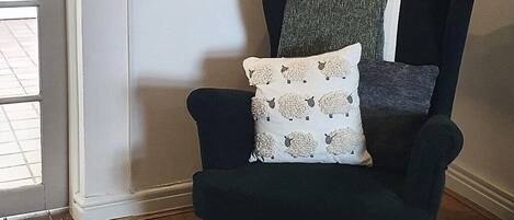 Un salón con un sillón oscuro, un pequeño reposapiés y un letrero en la pared con la palabra 'breathe'.