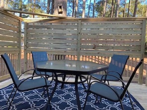 Relax in a serene outdoor setting surrounded by trees, with a comfortable table and chairs.