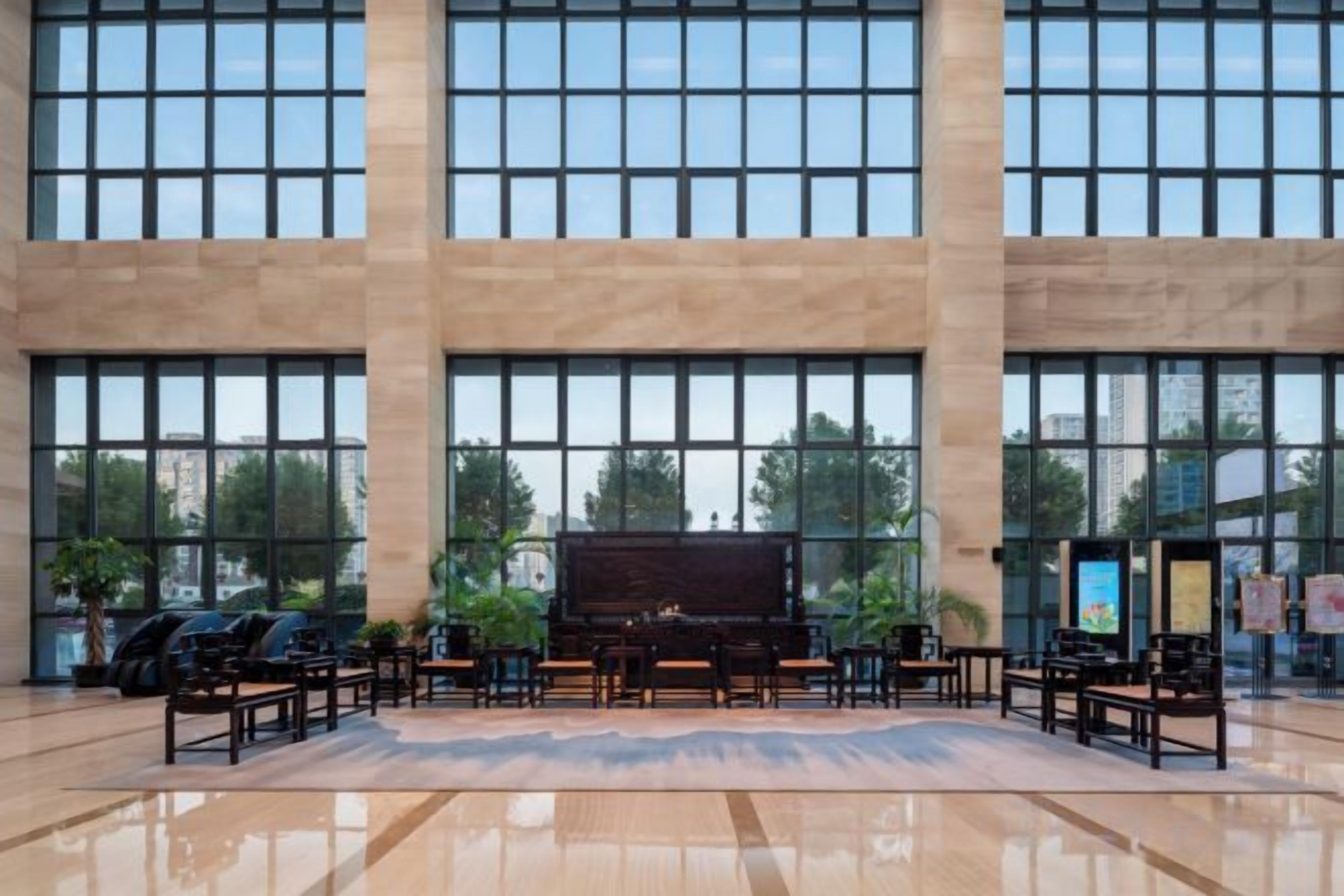 Eine geräumige Lobby mit großen Fenstern, einem Klavier und Sitzgelegenheiten.