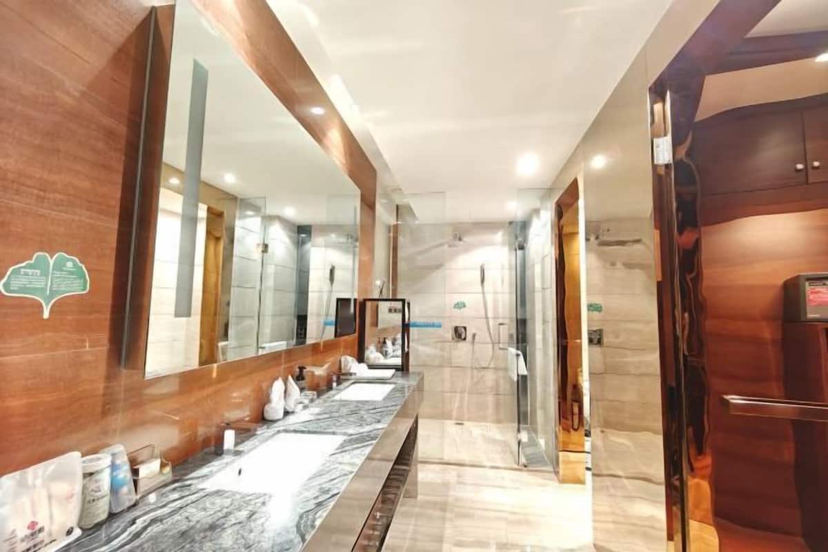 Un baño moderno con un tocador espacioso, un espejo grande y una zona de ducha.