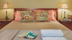 A neatly made bed with pillows, a folded towel, and a book on a bedside table. - Traditional apartement with pool for relaxation moments (Trikorfo xalkeias)