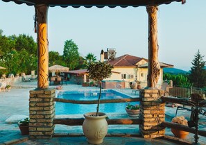 A pool area with a pergola, stone pillars, and a potted plant. - Traditional apartement with pool for relaxation moments (Trikorfo xalkeias)