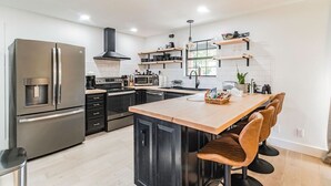 A modern kitchen with a central island, stainless steel appliances, and wooden bar stools. - Incredible view of Beaver Lake from the private hot tub (Garfield)