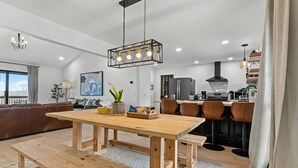 A modern kitchen with a wooden dining table, chairs, and a hanging light fixture. - Incredible view of Beaver Lake from the private hot tub (Garfield)