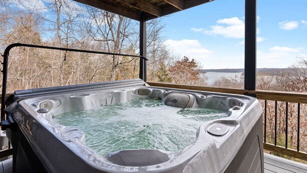 A hot tub on a wooden deck with a view of a lake and trees. - Incredible view of Beaver Lake from the private hot tub (Garfield)