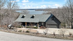 A two-story house with a sloped roof, a garage, and a view of a lake. - Incredible view of Beaver Lake from the private hot tub (Garfield)