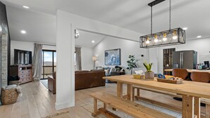 A spacious living area with a wooden dining table, benches, and a modern chandelier. - Incredible view of Beaver Lake from the private hot tub (Garfield)