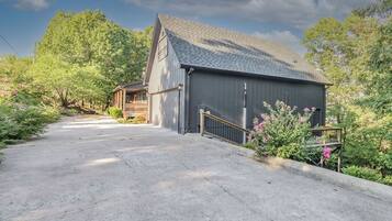 Un bâtiment à deux étages avec un garage, entouré d’une végétation luxuriante et de plantes en fleurs.