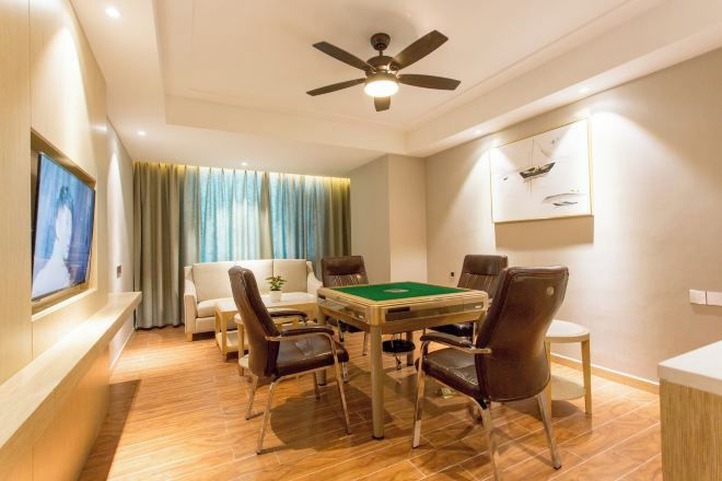 Una habitación con mesa de billar, cuatro sillas, ventilador de techo, televisor en la pared y una ventana con cortinas.