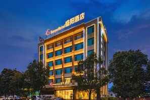 A multi-story hotel with a prominent sign at the top, multiple windows, and a parking lot in front. - Shengyang Hotel (Yuxi)