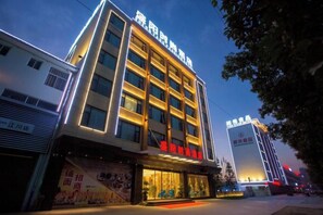 A multi-story hotel with illuminated signage, a prominent entrance, and a large display window. - Shengyang Hotel (Yuxi)