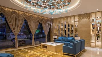 A modern hotel lobby with a blue sofa, a coffee table, and a decorative ceiling light fixture.