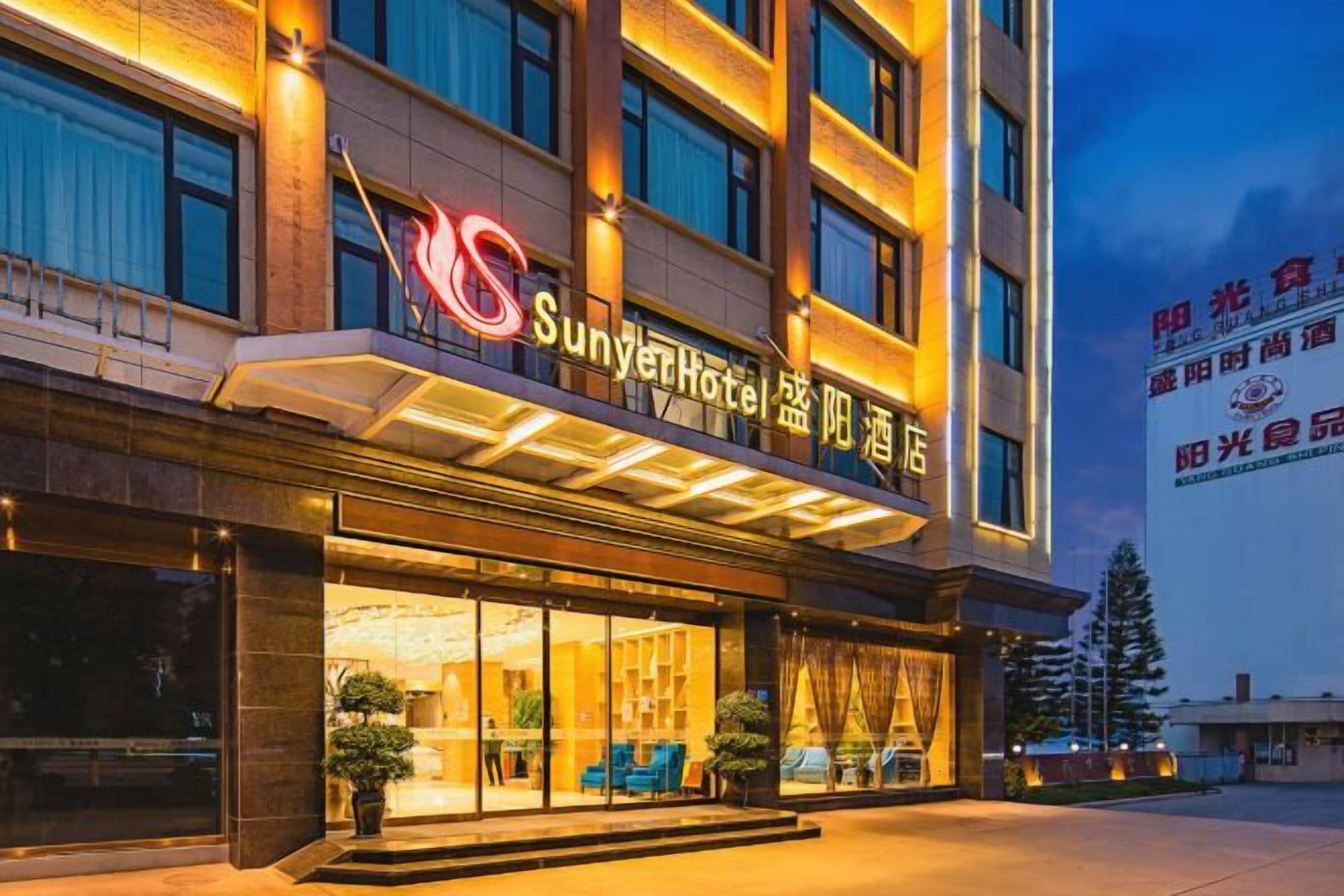 Een hotel met een opvallend bord, grote ramen en een overdekte entree.